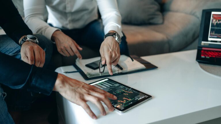 Two businessmen using a tablet to analyze financial data indoors.